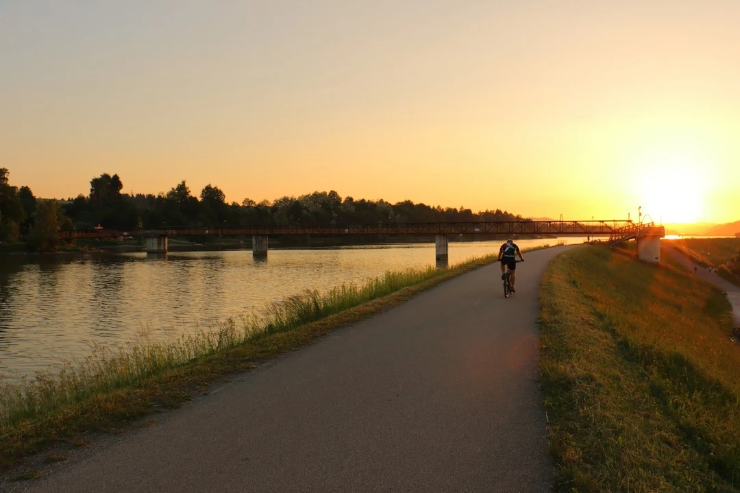 Cyklista na hrádzi pri rieke pri západe slnka